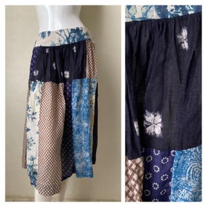 May include: A patchwork skirt with a blue, brown, and white floral pattern. The skirt is made of different fabrics and has a gathered waist.