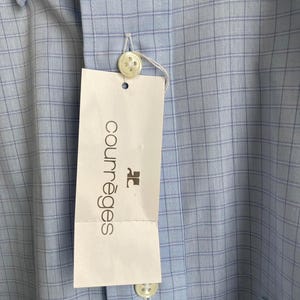 May include: A light blue button-down shirt with a white and light blue checkered pattern. The shirt has a white tag with the text "Courr&egrave;ges" in black.