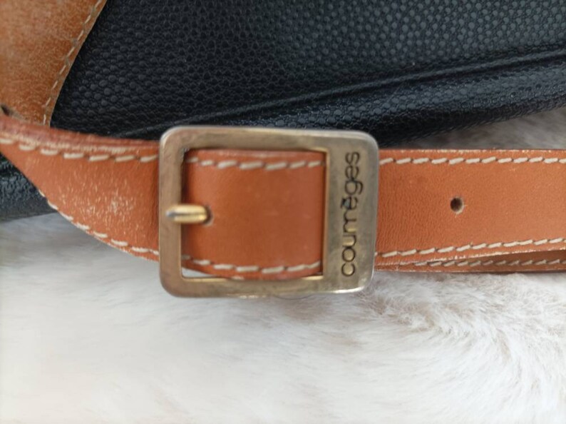 May include: A brown leather strap with a gold-toned buckle and the word "Courr&egrave;ges" engraved on it.