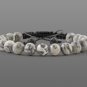 May include: A gray and white agate beaded bracelet with black lava beads and a black cord.