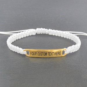 May include: White braided cord bracelet with a gold metal bar that says "YOUR CUSTOM TEXT HERE".
