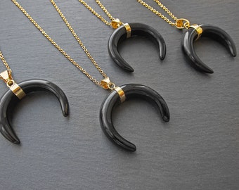 May include: Four gold necklaces with black crescent moon pendants. The pendants have a gold trim around the edge.