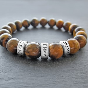 May include: Tiger's eye beaded bracelet with three silver beads engraved with the names "Liam", "Emma", and "Noah".