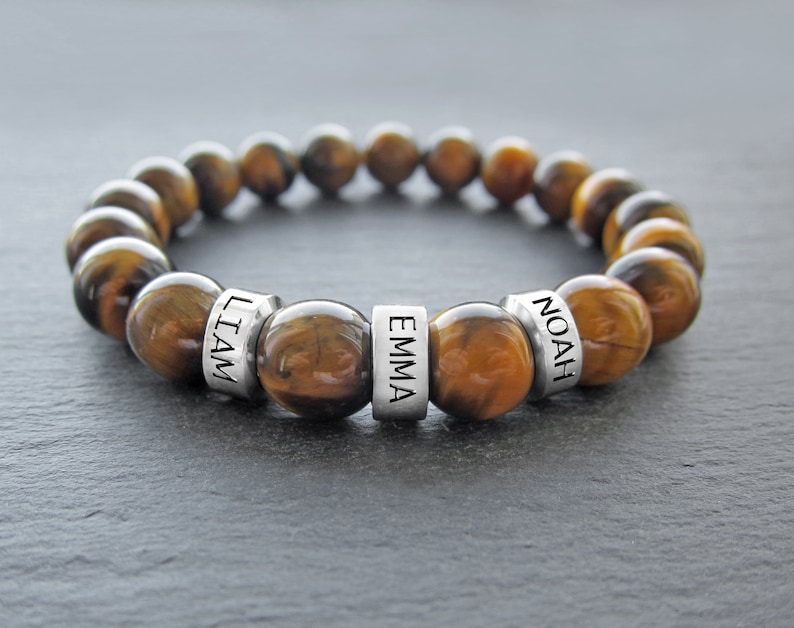 May include: Tiger's eye beaded bracelet with three silver beads engraved with the names "Liam", "Emma", and "Noah".