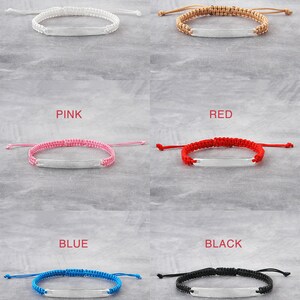 May include: Six braided bracelets with a silver nameplate. The bracelets are in the colours white, beige, pink, red, blue, and black.