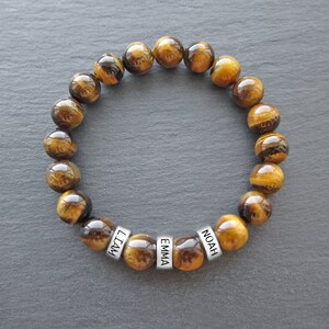 May include: Tiger's eye beaded bracelet with silver name beads that read "Liam", "Emma", and "Noah".