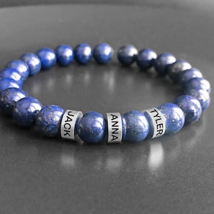 May include: A blue lapis lazuli beaded bracelet with silver beads engraved with the names "JACK", "ANNA", and "TYLER".