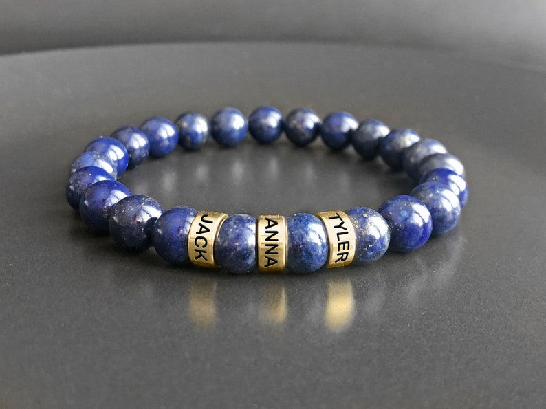 May include: A blue lapis lazuli beaded bracelet with gold beads that have the names "Jack", "Anna", and "Tyler" engraved on them.