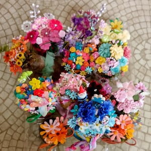 May include: A collection of 10 miniature flower arrangements in various colors, including pink, blue, yellow, and green. Each arrangement is made with artificial flowers and is displayed in a small pot. Some arrangements feature decorative accents like a gnome or a ladybug.