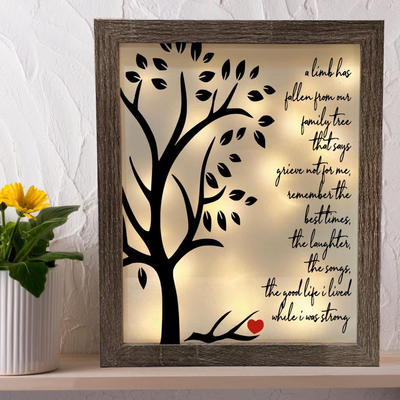 May include: A wooden framed light-up wall decor with a black silhouette of a tree with leaves and a red heart on a branch. The text reads "a limb has fallen from our family tree that says grieve not for me, remember the best times, the laughter, the songs, the good life I lived while I was strong."