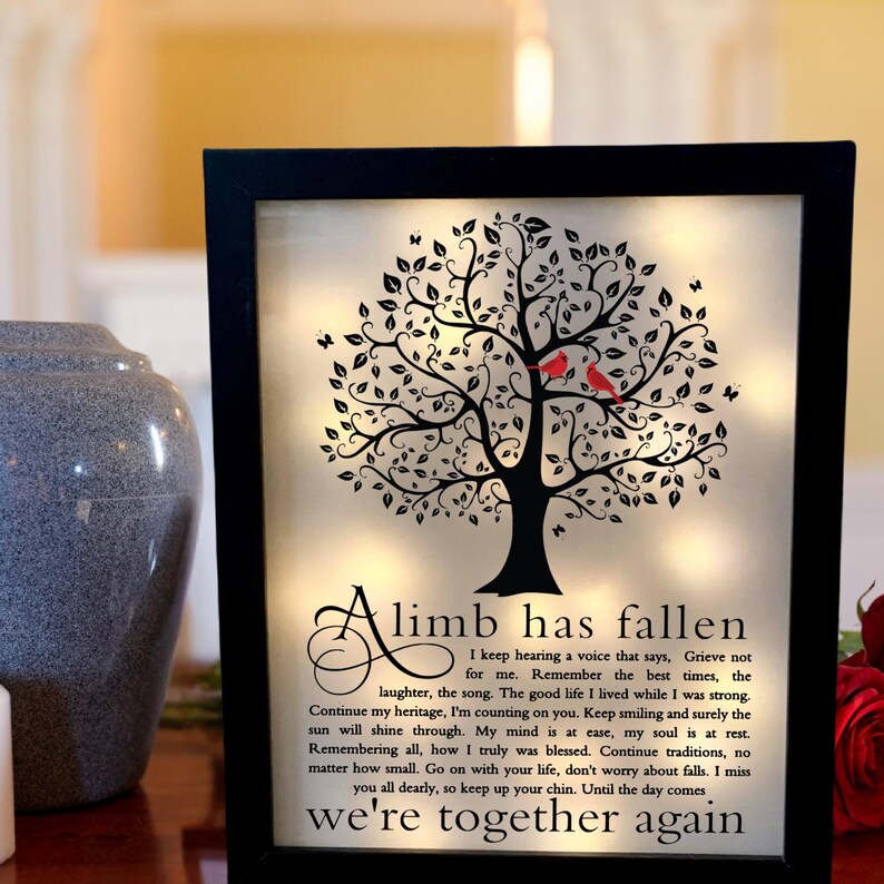 May include: A black framed illuminated memorial with a black silhouette of a tree with red cardinals perched on a branch. The text reads "A limb has fallen. I keep hearing a voice that says, Grieve not for me. Remember the best times, the laughter, the song. The good life I lived while I was strong. Continue my heritage, I'm counting on you. Keep smiling and surely the sun will shine through. My mind is at ease, my soul is at rest. Remembering all, how I truly was blessed. Continue traditions, no matter how small. Go on with your life, don't worry about falls. I miss you all dearly, so keep up your chin. Until the day comes we're together again."