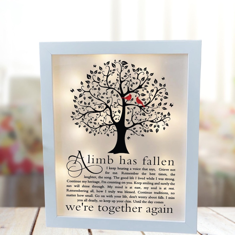 May include: A white framed illuminated memorial with a black silhouette of a tree with red birds perched on the branches. The text reads "A limb has fallen I keep hearing a voice that says, Grieve not for me. Remember the best times, the laughter, the song. The good life I lived while I was strong. Continue my heritage, I'm counting on you. Keep smiling and surely the sun will shine through. My mind is at ease, my soul is at rest. Remembering all, how I truly was blessed. Continue traditions, no matter how small. Go on with your life, don't worry about falls. I miss you all dearly, so keep up your chin. Until the day comes we're together again"