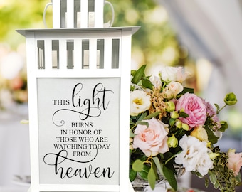 May include: White lantern with a gray background and black text that reads "This light burns in honor of those who are watching today from heaven".