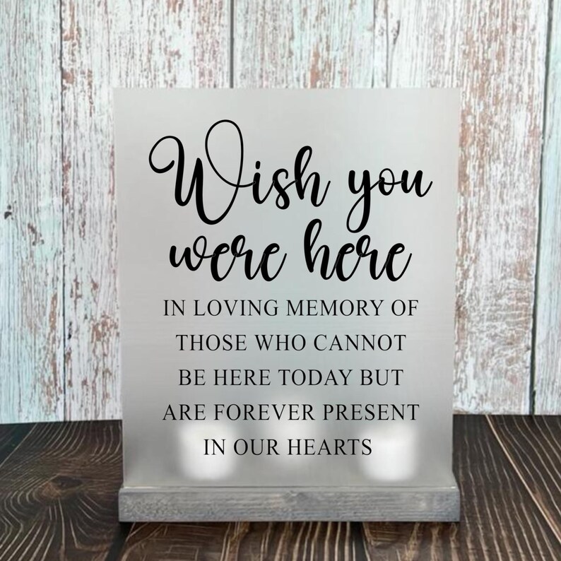 May include: A white sign with black text that reads "Wish you were here. In loving memory of those who cannot be here today but are forever present in our hearts."