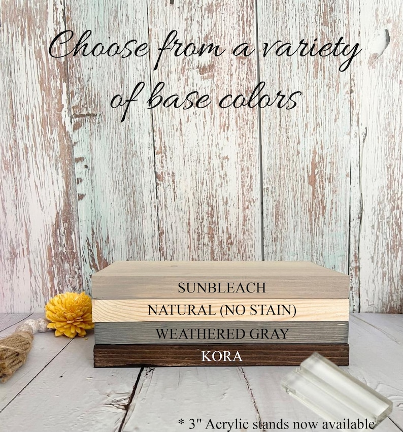 May include: Four wooden boards stacked on top of each other, showing different wood stain colors. The colors are Sunbleach, Natural (No Stain), Weathered Gray, and Kora. The text "* 3" Acrylic stands now available" is at the bottom of the image.