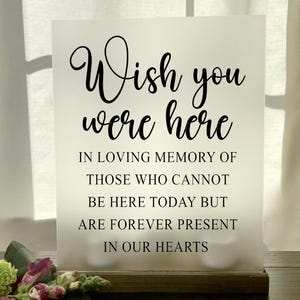 May include: White frosted sign with black text that reads "Wish you were here. In loving memory of those who cannot be here today but are forever present in our hearts."