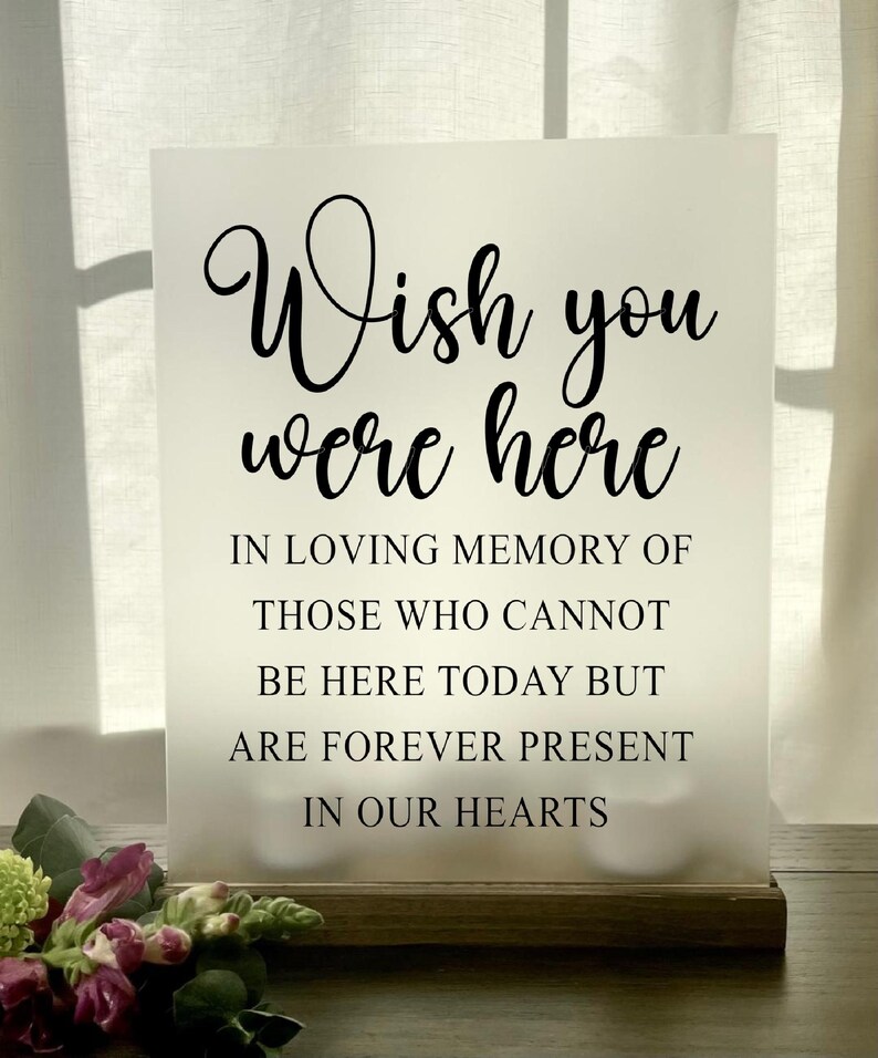 May include: White frosted sign with black text that reads "Wish you were here. In loving memory of those who cannot be here today but are forever present in our hearts."
