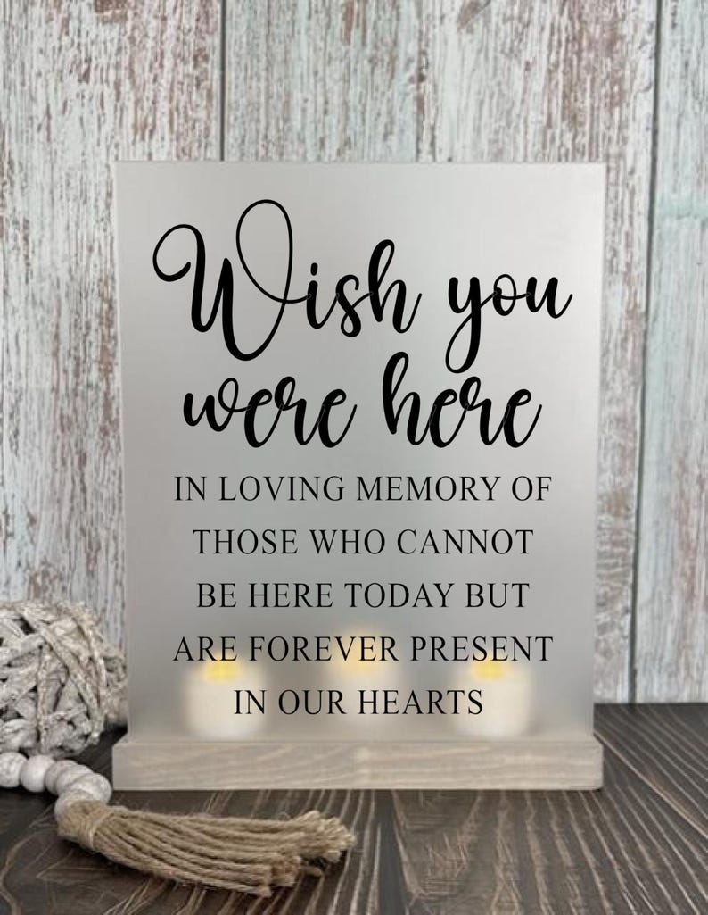 May include: A white sign with black text that reads "Wish you were here. In loving memory of those who cannot be here today but are forever present in our hearts."