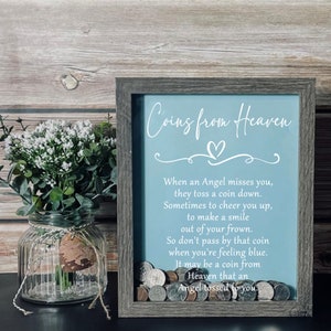 May include: A framed shadow box with a light blue background and white text that reads "Coins from Heaven". The text continues with a poem about finding coins and how they may be a sign from an angel. The shadow box is filled with coins.