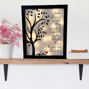 May include: A black framed illuminated wall art piece with a silhouette of a tree and a red heart on a branch. The text reads "A limb has fallen from our family tree that says grieve not for me, remember the best times, the laughter, the songs, the good life I lived while I was strong."