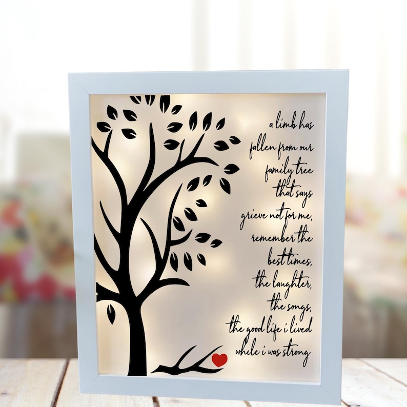 May include: A white framed light-up memorial with a black silhouette of a tree with a red heart on a branch. The text reads: "A limb has fallen from our family tree that says grieve not for me, remember the best times, the laughter, the songs, the good life I lived while I was strong."