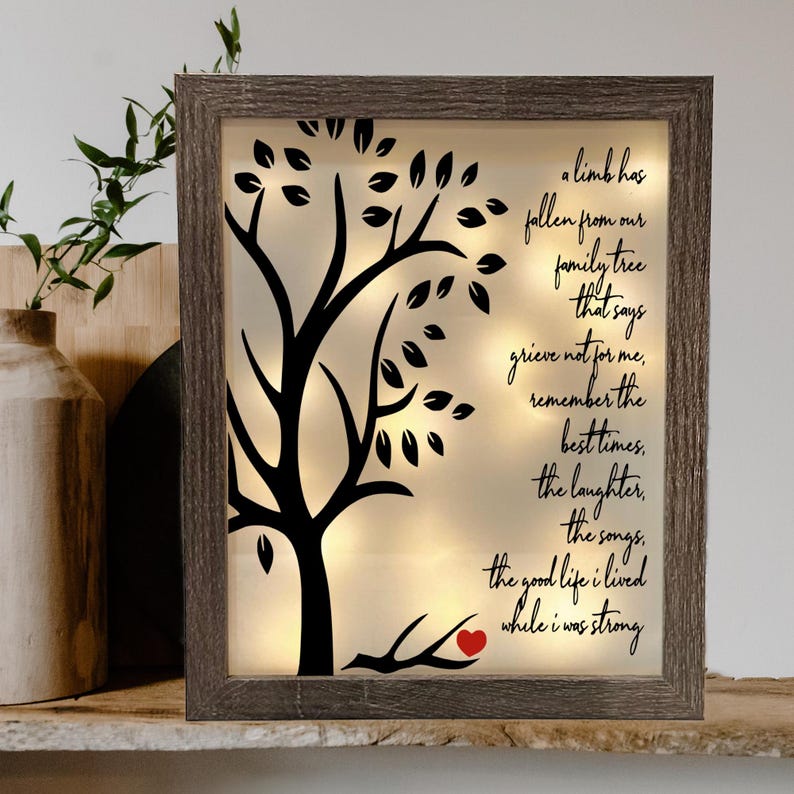 May include: A framed light-up wall decor with a black silhouette of a tree with leaves and a red heart on a branch. The text reads "A limb has fallen from our family tree that says grieve not for me, remember the best times, the laughter, the songs, the good life I lived while I was strong."