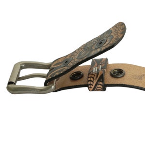 May include: A brown leather belt with a floral design and a silver buckle. The belt has multiple holes for adjusting the size.