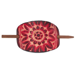 Puede incluir: Un palo para el pelo de cuero rojo y negro con un diseño floral. El palo es de madera.