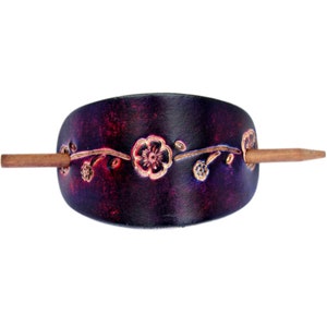 May include: A dark purple leather hair stick with a floral design and a wooden pin.