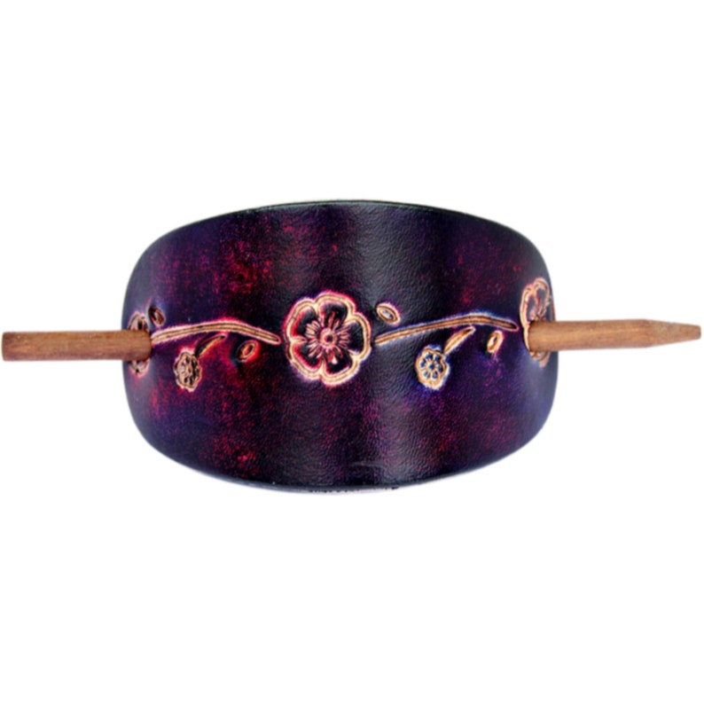 May include: A dark purple leather hair stick with a floral design and a wooden pin.