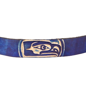 May include: A blue leather bracelet with a carved eagle design. The bracelet has silver metal snaps on each end.