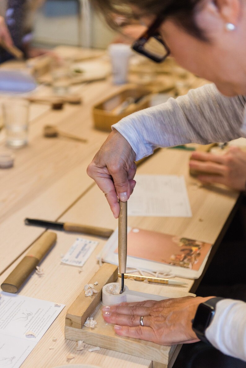 Spoon gouge being used to carve out bowl to spoon on a bench hook.