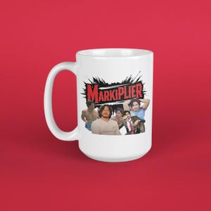 Puede incluir: Taza de café de cerámica blanca con un gráfico en blanco y negro de un grupo de hombres con el texto "Markiplier" en rojo.