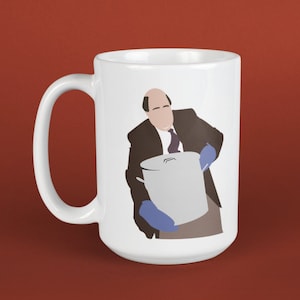 Può includere: Tazza in ceramica bianca con un'illustrazione di un uomo calvo in abito marrone e guanti blu che tiene una grande pentola d'argento.