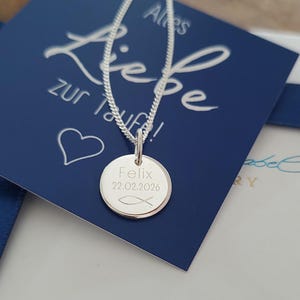 May include: A silver necklace with a circular pendant. The pendant is engraved with the name "Felix", the date "22.02.2026", and a fish symbol. The necklace is displayed on a blue card with white script.