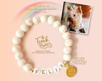 May include: White howlite bead bracelet with gold accents and a gold paw print charm. The bracelet has the name "Felix" spelled out in gold letters on white beads. The text "Frank & Beanz" and "Howlite Cream - Pet Memorial Bracelet" is printed in gold on a white background. The text "Keep your fur baby's memory where ever you go" is printed in gold on a white background.