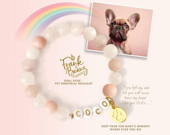 May include: A pink and white beaded bracelet with a gold charm that says "COCO" and a paw print. The bracelet is a pet memorial bracelet and is part of the Frank & Bean collection. The text on the charm reads "You left my side but you will never leave my heart. Miss you Coco... Keep your fur baby's memory where ever you go."