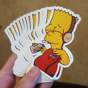 May include: A stack of yellow and red cartoon stickers featuring a character with yellow hair, a red shirt, and headphones. The character is holding a green and white object and a cigarette.