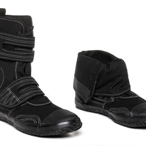 May include: A pair of black canvas high-top shoes with white stitching and a velcro strap. The shoes have a thick rubber sole.
