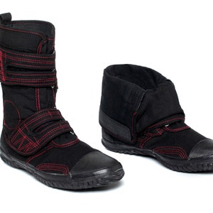 May include: A pair of black canvas high-top shoes with red stitching and adjustable straps. The shoes have a rounded toe and a thick rubber sole.
