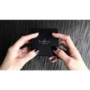 May include: A black square box with the text "la Ren&eacute;e Jewellery" in white lettering.