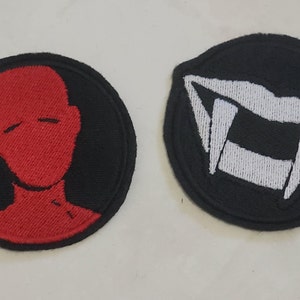 May include: Two embroidered iron-on patches. One patch is black with a red silhouette of a person's head. The other patch is black with a white embroidered image of a set of fangs.