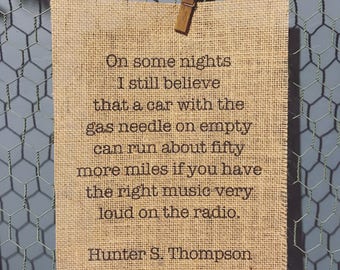 Op de afbeelding: Een juteprint met een citaat van Hunter S. Thompson dat luidt: "On some nights I still believe that a car with the gas needle on empty can run about fifty more miles if you have the right music very loud on the radio."