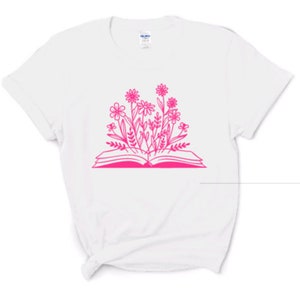 Peut inclure: T-shirt blanc avec un contour rose d'un livre ouvert avec des fleurs qui en sortent.