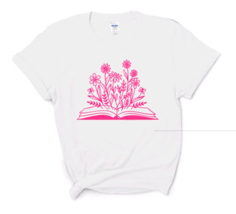 Peut inclure: T-shirt blanc avec un contour rose d'un livre ouvert avec des fleurs qui en sortent.