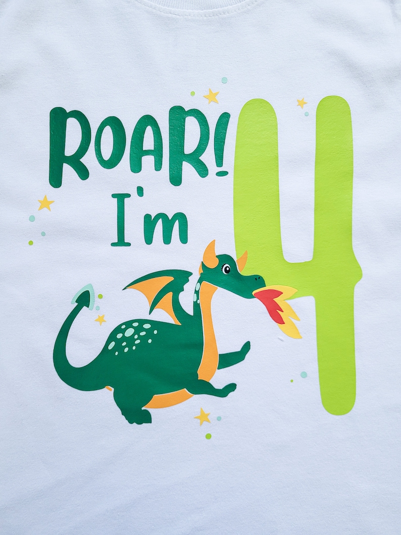 May include: White t-shirt with a green dragon and the text "Roar! I'm 4" in green letters. The number 4 is green and yellow.