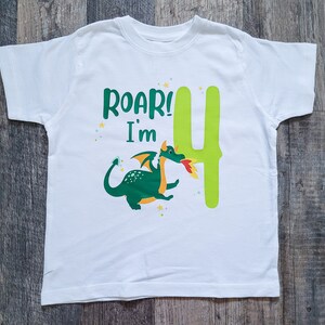 May include: White t-shirt with a green dragon and the text "Roar! I'm 4" printed on it.