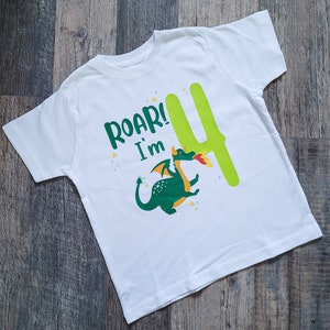 May include: White t-shirt with a green dragon and the text "Roar! I'm 4" in green and yellow letters.