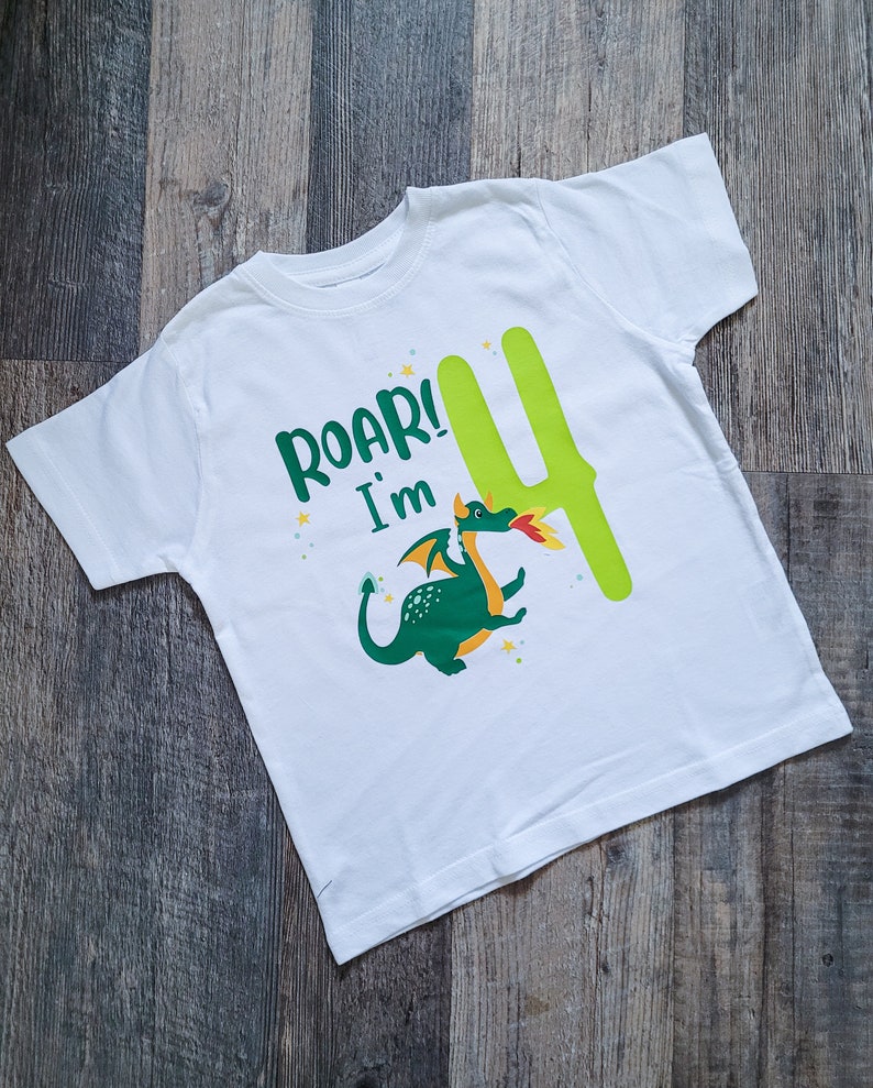 May include: White t-shirt with a green dragon and the text "Roar! I'm 4" in green and yellow letters.