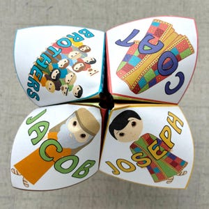 May include: A white paper fortune teller with colorful illustrations and text. The fortune teller features the words "Brothers", "Coat", "Jacob", and "Joseph" with corresponding images of people and a coat.